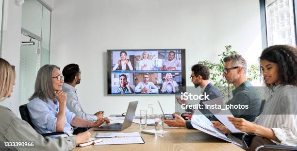 Diverse Employees On Online Conference Video Call On Tv Screen In Meeting Room - Fotografias de stock e mais imagens de Reunião