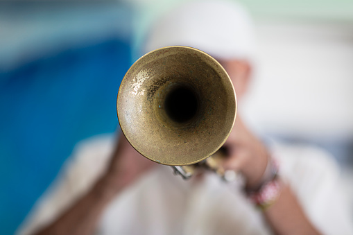 In Old Havana, with focus on the instrument, a senior Cuban musician is gladly playing his trumpet.