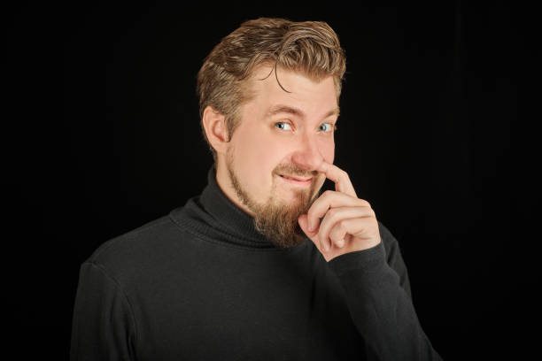 istock Funny bearded man picking his nose, black background 1333393516