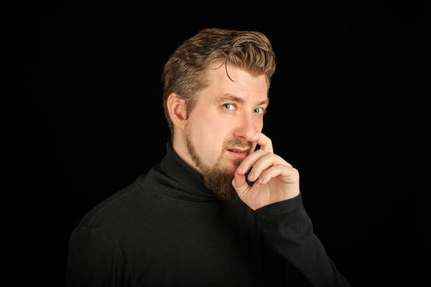 istock Funny bearded man picking his nose, black background 1333393567