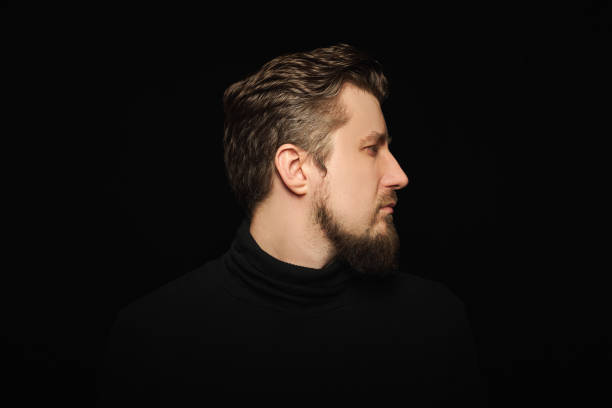 istock Thoughtful bearded man, half profile portrait, black background 1333393595