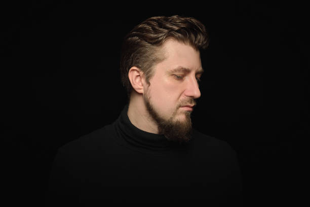 istock Thoughtful bearded man, half profile portrait, black background 1333393600