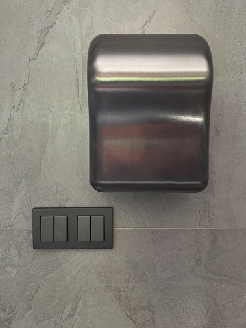 Hand dryer and electrical switch on the wall background
