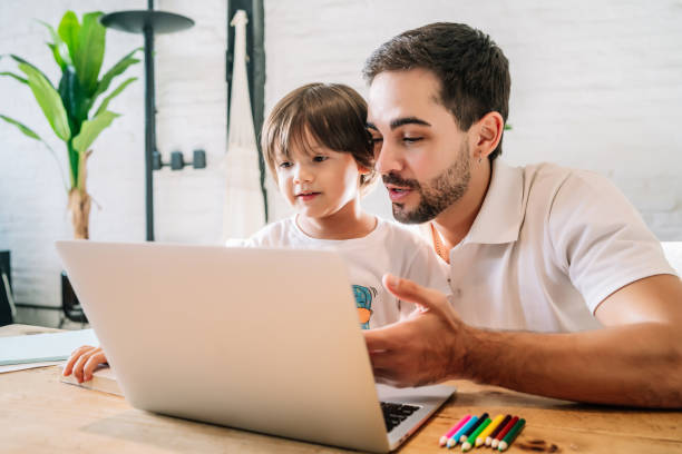 istock Little boy and his father using a laptop at home. 1333398828