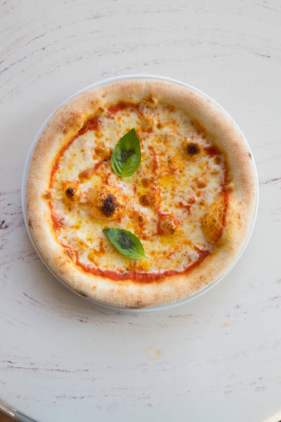 istock Fresh baked whole round pizzawith basil leaf 1333398854