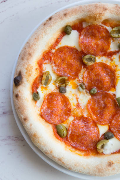 istock Whole round neapolitan pepperoni pizza served on a table 1333399115