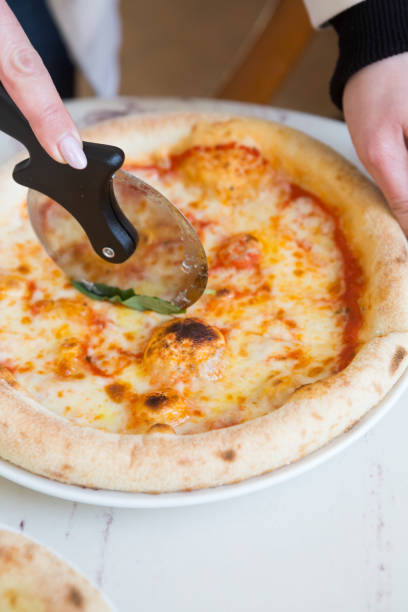 istock Woman hand holding knife and cutting pizza 1333399122