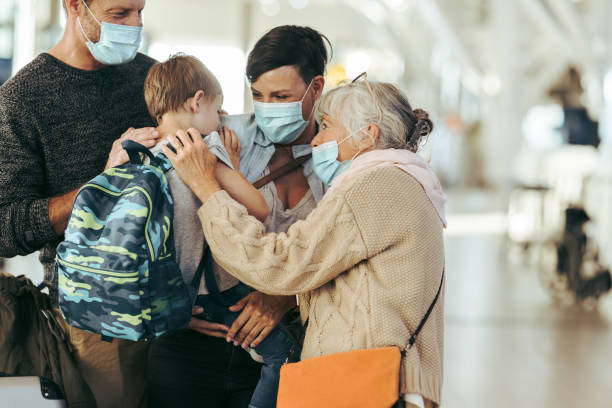 Reunion of family at airport post pandemic Senior woman talking with her grandchild at airport. Woman with her son and husband meeting with her mother at airport in pandemic. family reunion stock pictures, royalty-free photos & images