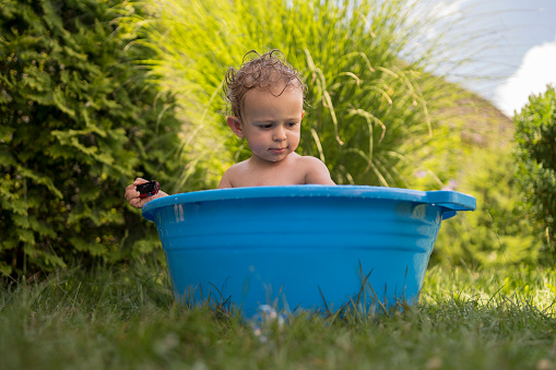 Cute boy enjoying bathing with soap foam and playing toys. Concept of family time, children development and fun at home.