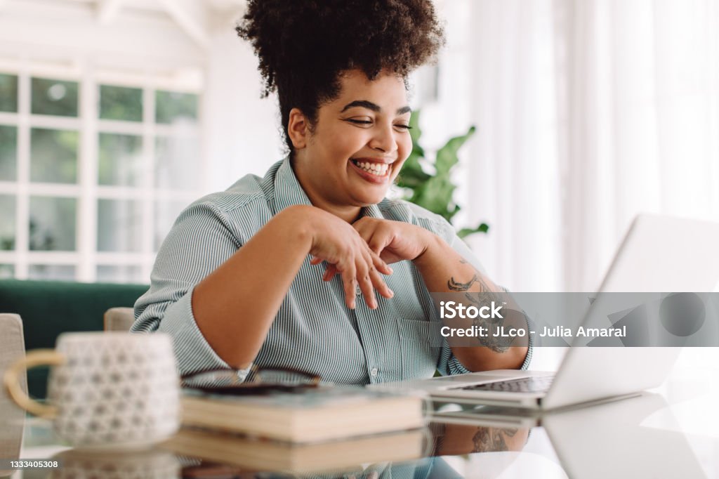 Positive woman video calling using laptop at home Positive woman video calling using laptop. Businesswoman teleconferencing on laptop while working from home. Women Stock Photo