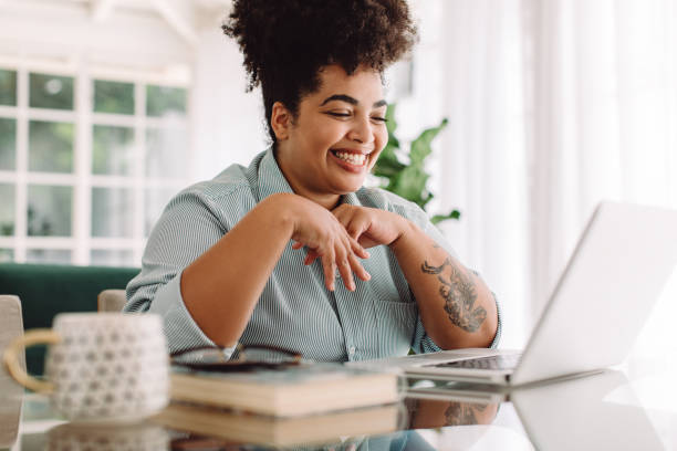 Positive woman video calling using laptop at home Positive woman video calling using laptop. Businesswoman teleconferencing on laptop while working from home. black people stock pictures, royalty-free photos & images