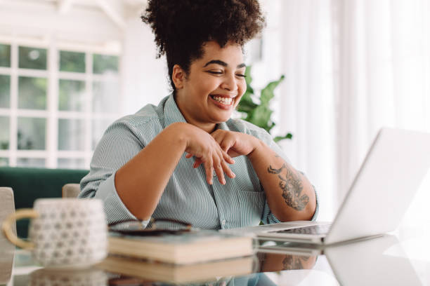 Positive woman video calling using laptop at home Positive woman video calling using laptop. Businesswoman teleconferencing on laptop while working from home. business lifestyle stock pictures, royalty-free photos & images
