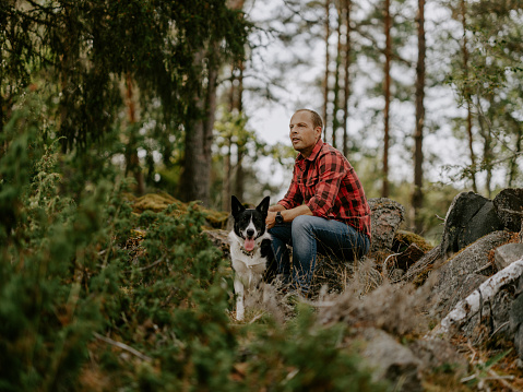 Man out in summer with his dog in beautiful forest nature\nCasual man outdoors in nature in rural setting