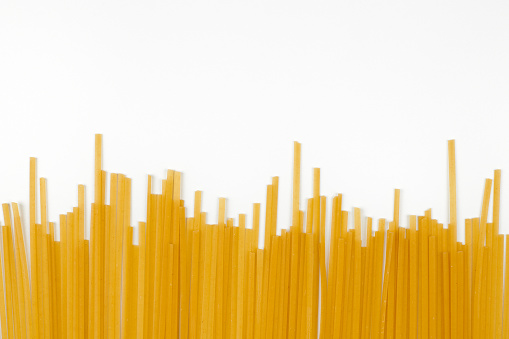 Uncooked spaghetti, white background. Bunch of italian pasta top view, flat lay.