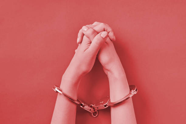 istock Crossed hands in handcuffs on red background 1333409248