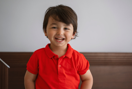 Close up portrait of a happy little boy looking at the camera and laughing