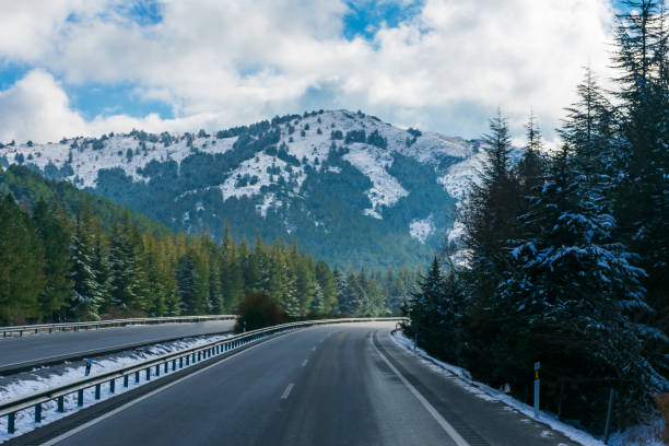 istock Highway between mountains and snow-covered forests. 1333416476