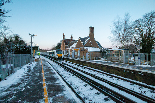 ThamesLink Train at Eynsford Railroad Station in Kent, England, with a snow shoveller on the platform
