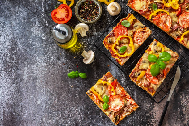 istock Homemade baking Detroit-Style pizza. Large rectangular Pepperoni pizza with mushrooms, salami and cheese on a stone tabletop. Top view flat lay background. Copy space. 1333418018
