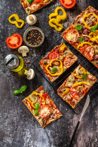 istock Homemade baking Detroit-Style pizza. Large rectangular Pepperoni pizza with mushrooms, salami and cheese on a stone tabletop. Top view flat lay background. Copy space. 1333418020