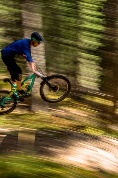 istock View of mountain biker getting air off jump in forest 1333426017