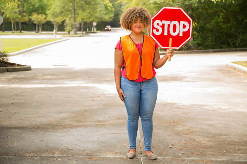 Back to School Road Crossing.   African American Safety Personnel holds up STOP sign for a safe crossing in the school zone.
