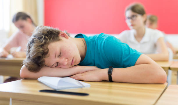 istock Bored teenage boy sleeping at desk in classroom during lesson 1333429751
