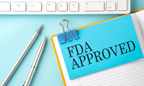 fda approved text auf aufkleber auf blauem hintergrund mit stift und tastatur - food and drug administration stock-fotos und bilder
