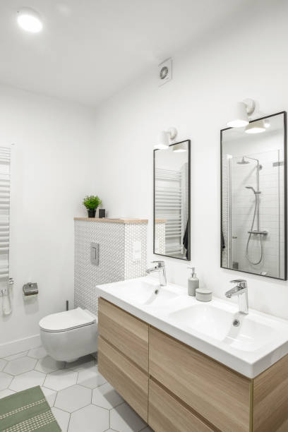 istock Modern minimalist bathroom interior design with white tiles, two white sinks and natural wood furniture 1333433633