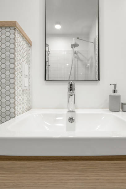 istock Modern minimalist bathroom interior design with white tiles, two white sinks and natural wood furniture 1333434011