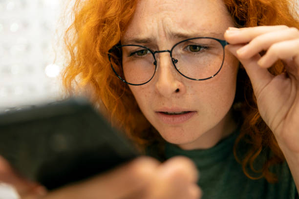 istock redhead young woman with eyesight problems trying to read phone text 1333437279
