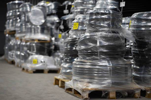 lack plastic pipes wrapped in foil on a pallet in a warehouse. pipe packaging ready for transportation. - industrislang bildbanksfoton och bilder