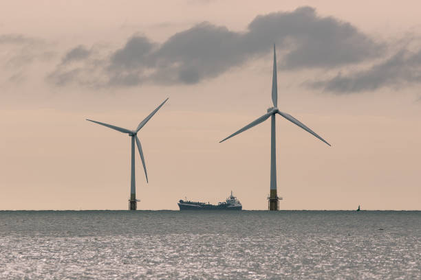 istock Pair of offshore wind farm wind turbines with supply ship 1333443357