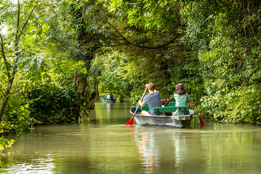 A young couple rowing the boat sailing between La Garette and Coulon, Marais Poitevin the Green Venice, near the town of Niort, France