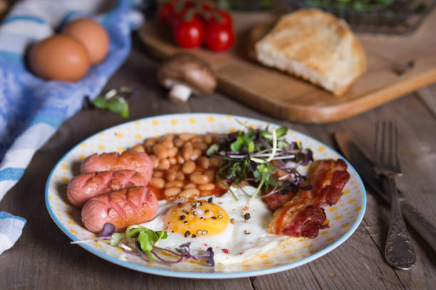 istock Fried eggs with bacon, sausages and beans in tomato sauce 1333445835