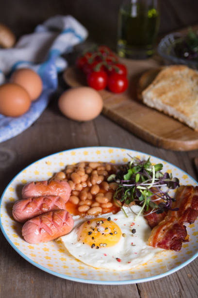 istock Fried eggs with bacon, sausages and beans in tomato sauce 1333445844