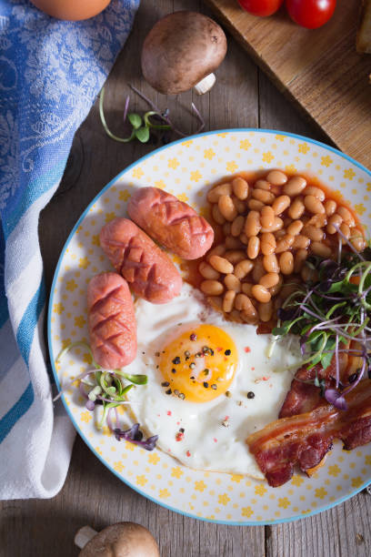 istock Fried eggs with bacon, sausages and beans in tomato sauce 1333445860