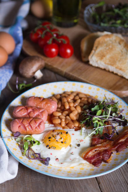 istock Fried eggs with bacon, sausages and beans in tomato sauce 1333445875