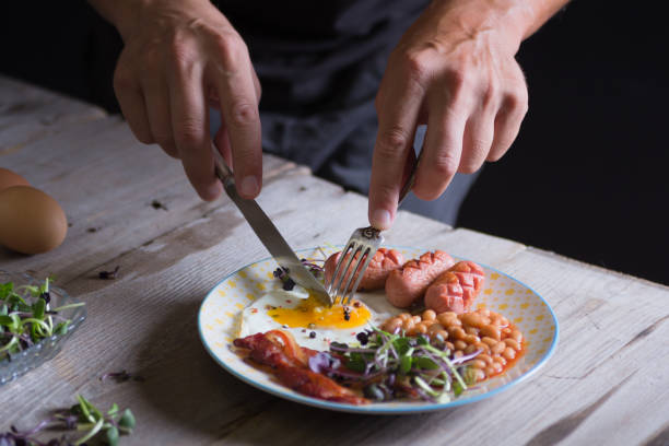 Man's hands are cutting a fried egg on a plate