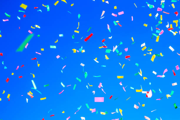 istock multicolored confetti on clear blue sky background. Concept of h 1333446833