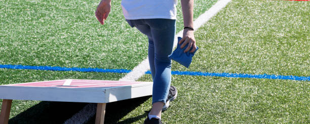 コーンホールを弾く青いビーンバッグを投げる人 - cornhole leisure games outdoors color image ストックフォトと画像