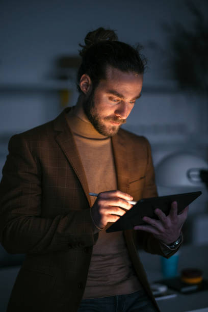 istock Handsome Businessman Standing in His Office Using a Digital Tablet During a Late Night at Work 1333458148