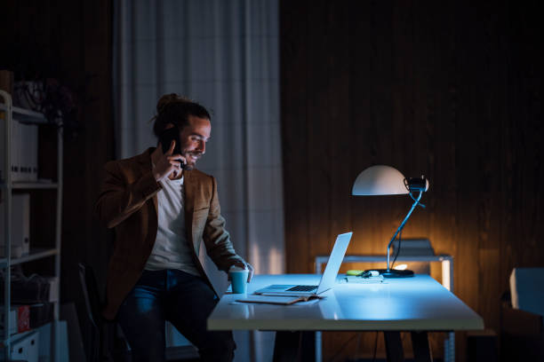 istock Handsome Young Businessman is Holding a Coffee Cup and Using his Laptop while Having a Phone Call 1333458182