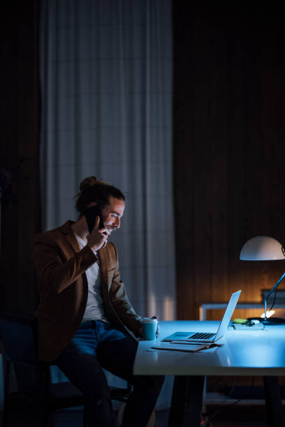 istock Handsome Young Businessman is Holding a Coffee Cup and Using his Laptop while Having a Phone Call 1333458184