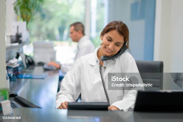 Receptionist Working At A Doctors Office And Talking On The Phone Stock Photo - Download Image Now