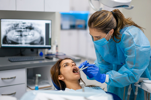 Latin American woman at the dentist getting her teeth examined and cleaned - medical treatment concepts