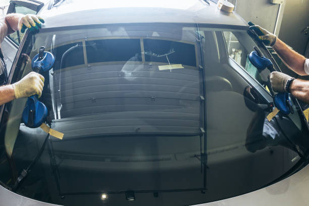 operai meccanici consegnano parabrezza rotto su nuovo parabrezza su auto in stazione di servizio da vicino - installing window glazier glass foto e immagini stock