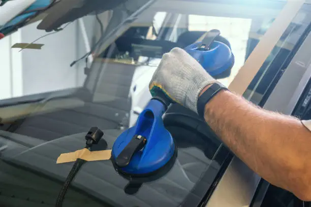 Photo of Mechanic changes windscreen or windshield on car close up