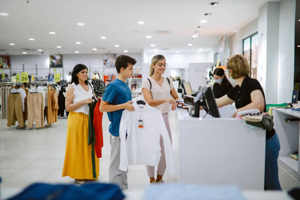 woman in late 30s paying contactless in the shopping mall - clothing store paying cashier credit card imagens e fotografias de stock