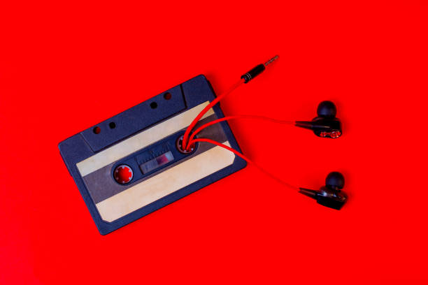 istock Old audio cassette and wired vacuum headphones on a red background. 1333479318